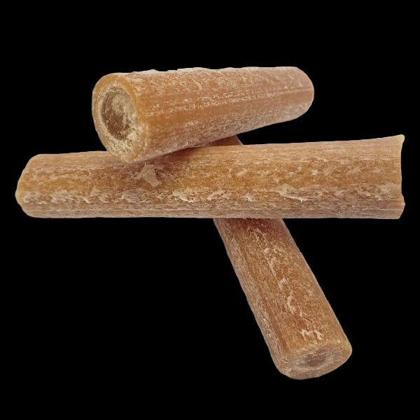 Three brown cylindrical dog treats on a white background